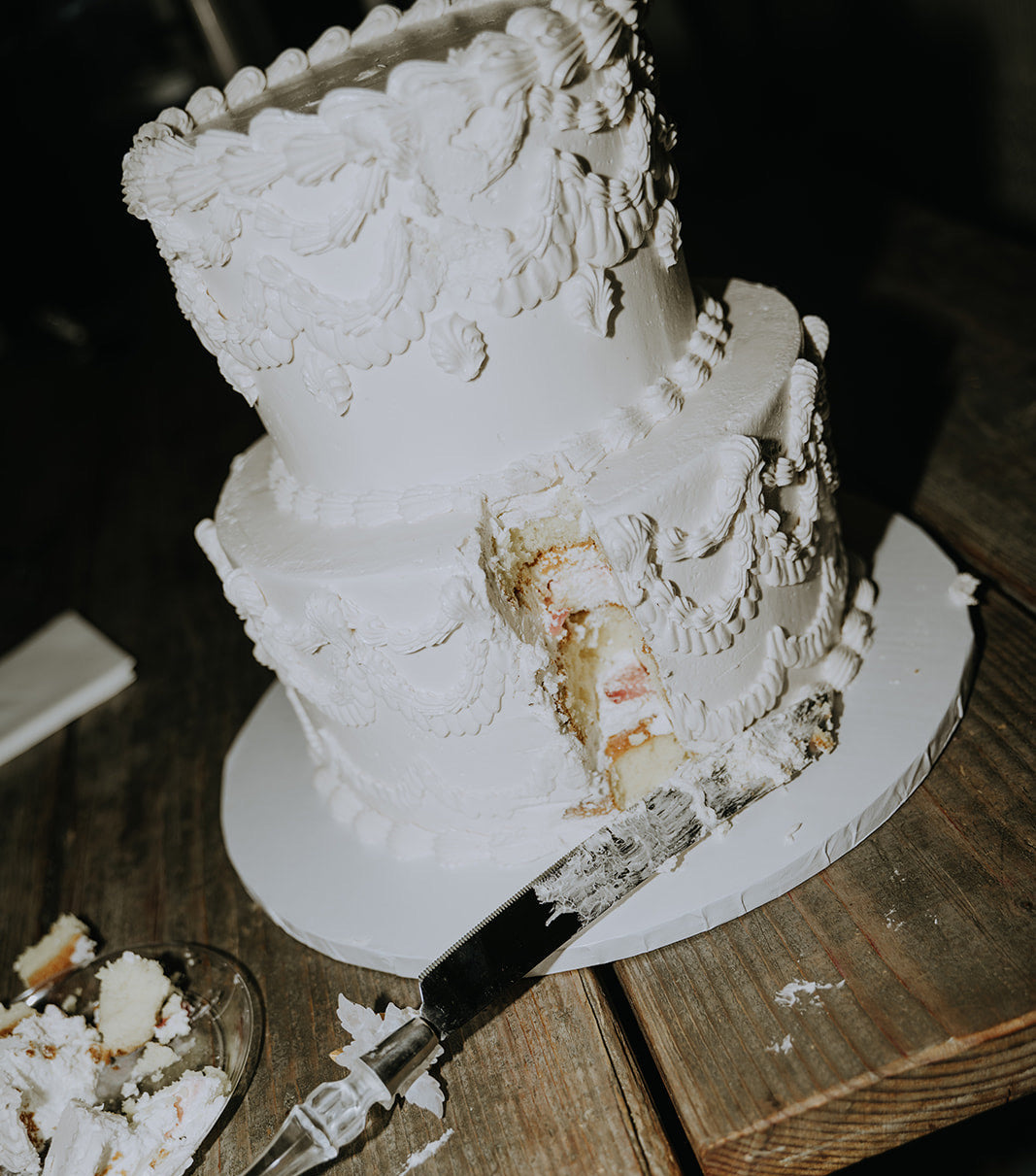 White wedding cake with a slice cut out on a wooden table